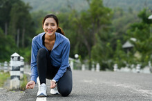 Smiling Sportswoman Tying Shoelaces Before Running, Getting Ready For Jogging Outdoors. Healthy Lifestyle Concept