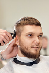 Poster - Barber trim hair with clipper on handsome bearded man