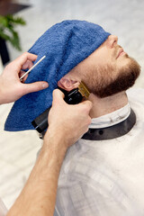 Poster - Barber shaving bearded man in barber shop.