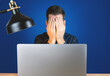 Mann hält die Hände vor das Gesicht vor Laptop, Burnout im Job