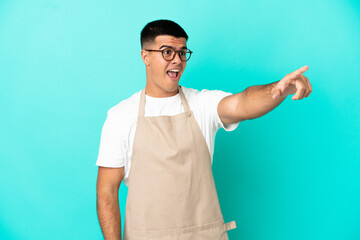 Wall Mural - Restaurant waiter man over isolated blue background pointing away