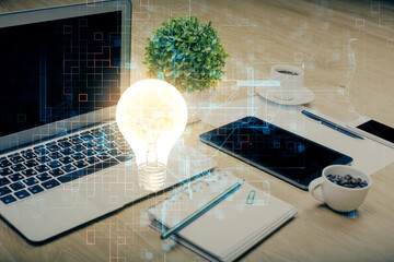 Poster - Computer on desktop in office with bulb icon hologram. Double exposure. Concept of idea.