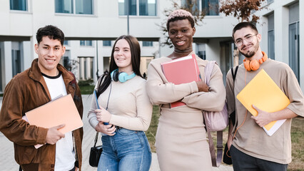 Happy multiethnic group of students smiling at the camera standing outside at the university campus