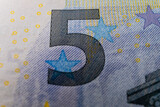 Fototapeta  - A macro image of the special ink on a Euro banknote, showcasing the security measures in place to prevent counterfeiting, including the multicolor microprint feature
