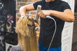 © PoppyPix - closeup view of a hairdresser holding a comb and a hairdryer and drying woman's blond hair. High quality photo