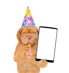 Poster - Mastiff puppy wearing party cap blowing in party horn, holds big smartphone with white blank screen in it paw, showing close to camera
