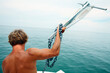 © Cavan Images - A man readies the anchor on a boat.