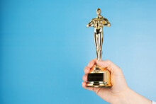 Oscar Statue, Award In Hand On Blue Background,copy Space