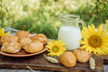 pies or buns and a mug of homemade farm fresh milk, sunflower, baked goods on a wooden background 6