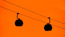 Silhouettes Of Ropeway, Cable Car Cabins Are Moving Against Warm Bright Orange Sky At Sunset In Batumi, Georgia - Aerial Rope Transit, Gondola Lift. Cableway, Sightseeing And Transportation Concept