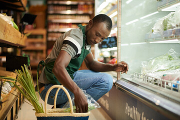 Wall Mural - Supermarket worker checking food quality and putting expired products in basket