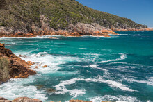 Turquoise Waves Splash On The Rocky Shore Along The Bay Of Fires