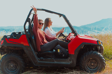 Two young happy excited women enjoying beautiful sunny day while driving a off road buggy car on mountain nature