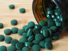 Spirulina pills on wooden background. Vitamins and dietary supplements. Food supplements for a healthy lifestyle