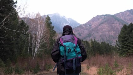 Wall Mural - concept of travel. a tourist with a backpack walks along a forest trail into the mountains. beautiful mountain landscape. an exciting hike in the mountains. enjoying nature. slow motion.