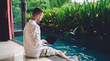 Male digital nomad working remotely at pool terrace enjoy freelance lifestyle, skilled graphic designer using wifi connection for doing distance job on mockup laptop with copy space area for website