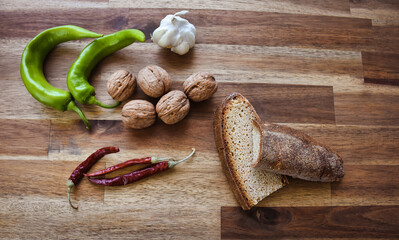 Shelled walnuts, red hot pepper, green sweet pepper a head of garlic, bread made from natural wheat on a wooden table. Healthy eating food low carb ketogenic diet plan.