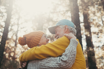 Sticker - Head shot portrait close up of old people smiling and enjoying looking each other in the forest of mountain. Cute couple of mature seniors in love feeling happy and taking care. Sun at the background