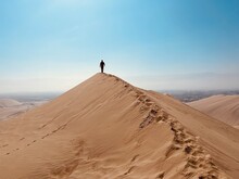 A Man Walks Along A Dune In The Desert. Huacachina, Peru
