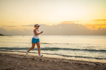 Wall Mural - Woman running on sunny, tropical beach at daybreak
