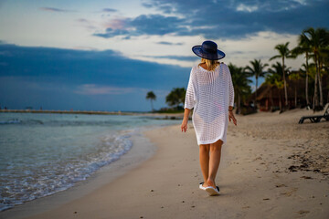 Wall Mural - Woman walking on sunny, tropical beach at daybreak
