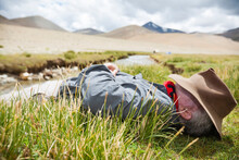 A Man Is Resting By A Stream In The Changtang Region Of Ladakh, India.