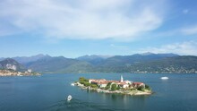 A Boat Joins The Island Isola Della Malghera On Lake Maggiore In Europe, Italy, Lombardy And Piedmont In Summer On A Sunny Day.