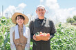 野菜を持った農業・農家・家庭菜園をするアジア人男女（移住・スローライフ・田舎暮らし・生産者）