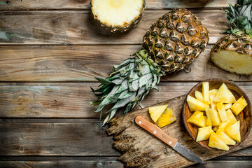 Poster - Sliced pineapple in a bowl on a cutting Board with a knife and a whole pineapple.