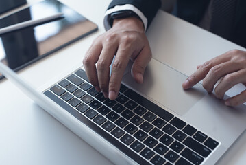 Wall Mural - Close up of businessman working with laptop computer on table at office. Business man hands typing on laptop, online working, surfing the internet