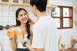 © DG PhotoStock - Happy cheerful Asian man and woman showing a half round of a fresh orange fruit to camera together and smiling.