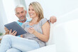 © Reese/peopleimages.com - Mature, happy couple or credit card on tablet banking, financial management or investment security in living room. Smile, relax man or woman on digital technology for house insurance or home loan tax