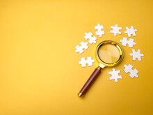 Magnifying Glass Searching Missing Puzzle On Yellow Background