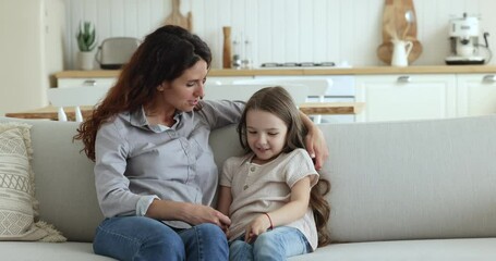 Wall Mural - Loving Hispanic mother talks to little daughter, hugs cute small child seated together on sofa, having pleasant warm conversation, gives motherly advice express care. Trust, family ties, understanding