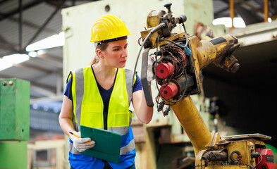 Wall Mural - caucasian female engineering worker wearing safety hardhat helmet inspecting auto robot lathe machine to drill components. Metal lathe industrial manufacturing factory