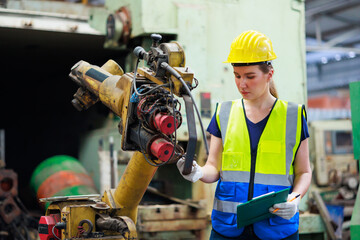 Wall Mural - caucasian female engineering worker wearing safety hardhat helmet inspecting auto robot lathe machine to drill components. Metal lathe industrial manufacturing factory