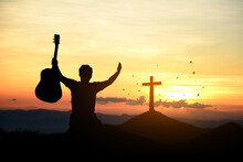 Man Standing Holding Christian Cross For Worshipping God At Sunset Background. Christian Silhouette Concept.