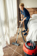 © Dusan Petkovic - The maid is vacuuming hotel room.