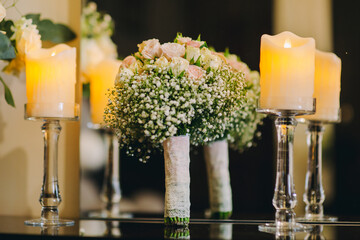 Wedding table with bouquet of white roses and burning candle .Evening Photo