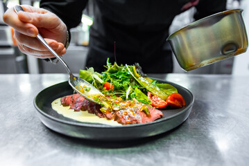 Poster - chef hand preparing Roastbeef salad with vegetables on restaurant kitchen