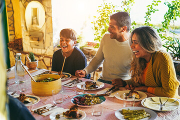 Wall Mural - Happy latin family having fun eating together during home dinner - Soft focus on father hands