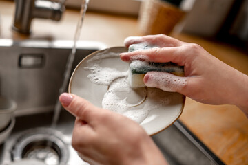 Girl washing dishes at kitchen at home