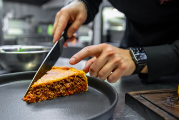 Wall Mural - chef hand preparing a gourmet meat pie on restaurant kitchen