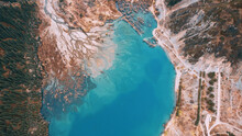 Top View Of The Turquoise Water Of A Mountain Lake. Clean Clear Water With Streaks On The Bottom. Patterns From A Mountain River. The Color Shimmers From Blue-green To Blue. Trees In The Water. Issyk