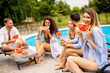 © BGStock72 - Young people sitting by the swimming pool and eating watermelon in the house backyard