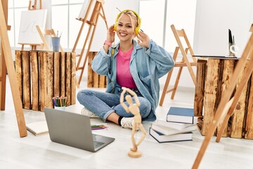 Poster - Young caucasian woman artist listening to music sitting on floor at art studio