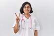 © Krakenimages.com - Young hispanic doctor woman wearing stethoscope over isolated background showing and pointing up with fingers number two while smiling confident and happy.