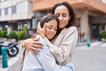 Wall Mural - Woman and girl mother and daughter hugging each other at street