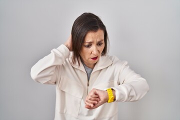 Canvas Print - Middle age hispanic woman standing over isolated background looking at the watch time worried, afraid of getting late