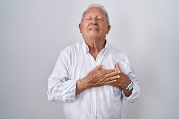 Sticker - Senior man with grey hair standing over isolated background smiling with hands on chest with closed eyes and grateful gesture on face. health concept.